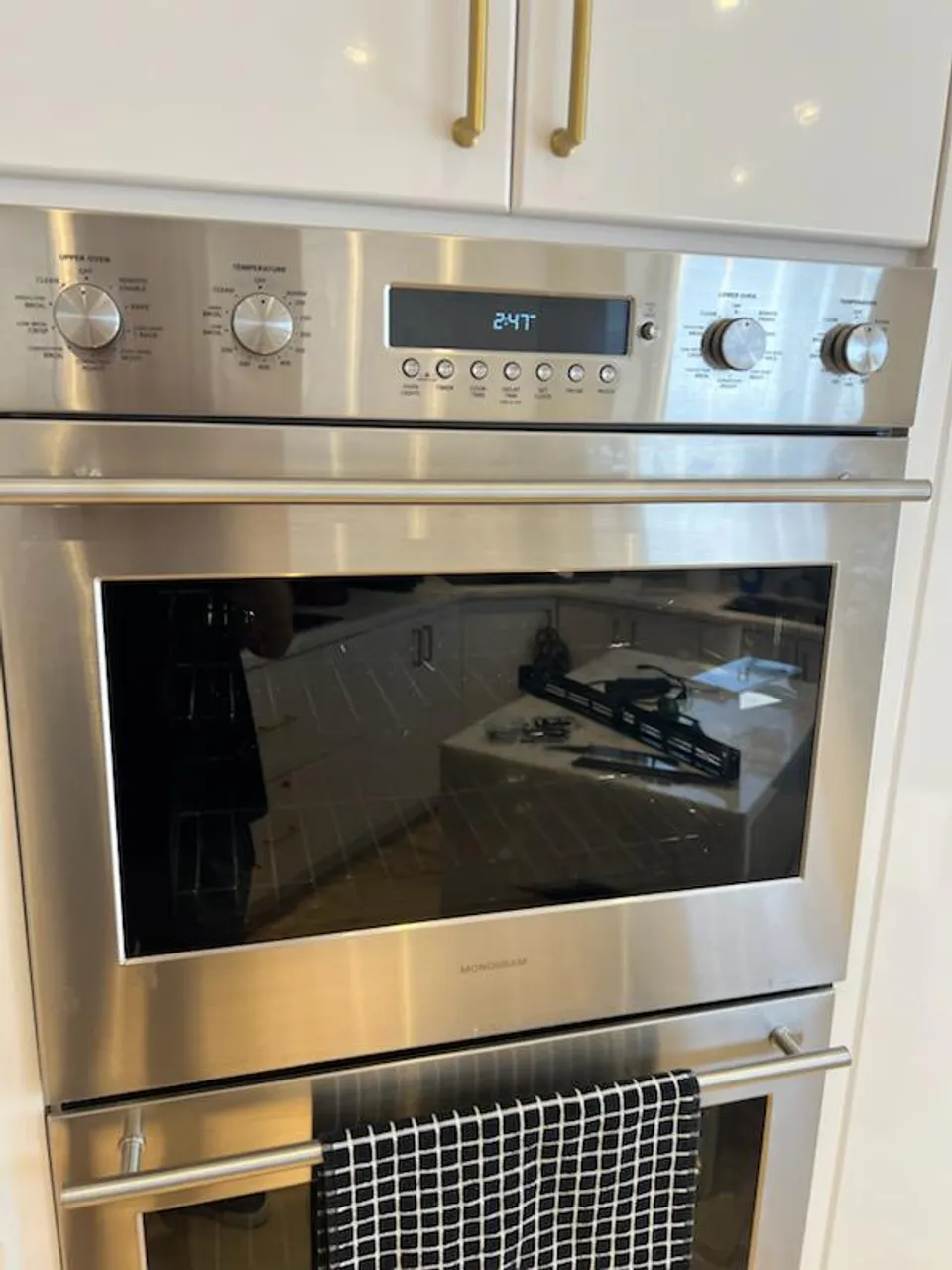 Built-in GE Monogram double wall oven in a white kitchen with brass hardware