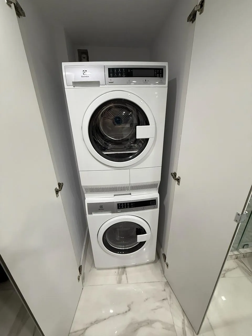Compact Electrolux washer and dryer stacked inside a mirrored closet