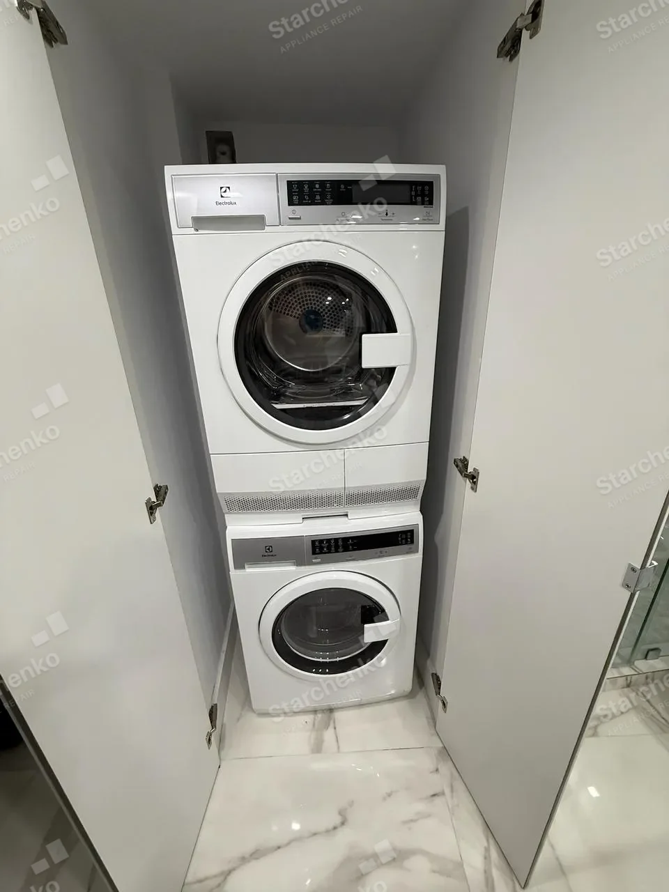 Compact Electrolux washer and dryer stacked inside a mirrored closet