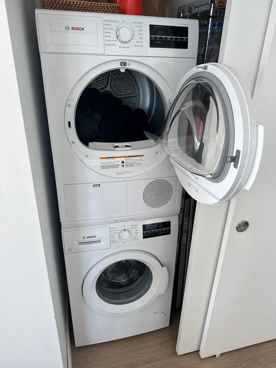 White Bosch dryer stacked above a washer with the dryer door open