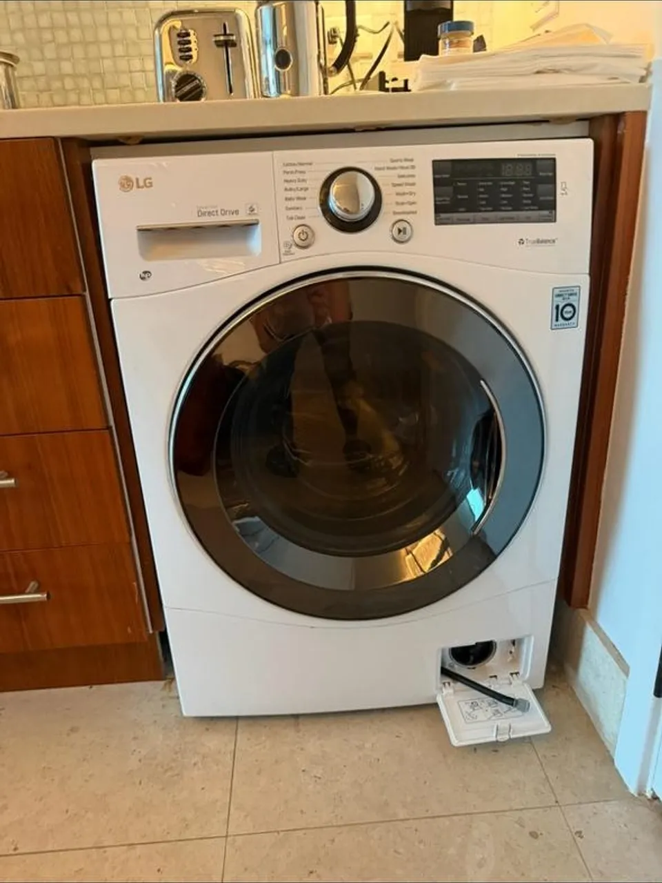 White LG front-load washer built under a counter with its lower service door open