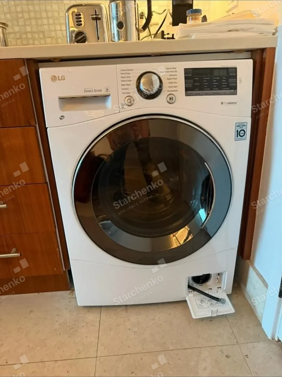White LG front-load washer built under a counter with its lower service door open