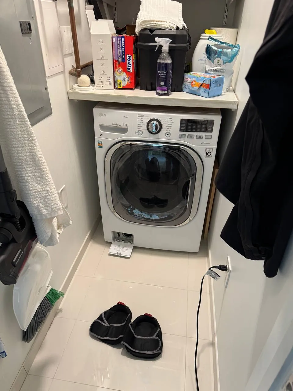 White LG front-load washer beneath a shelf of laundry supplies