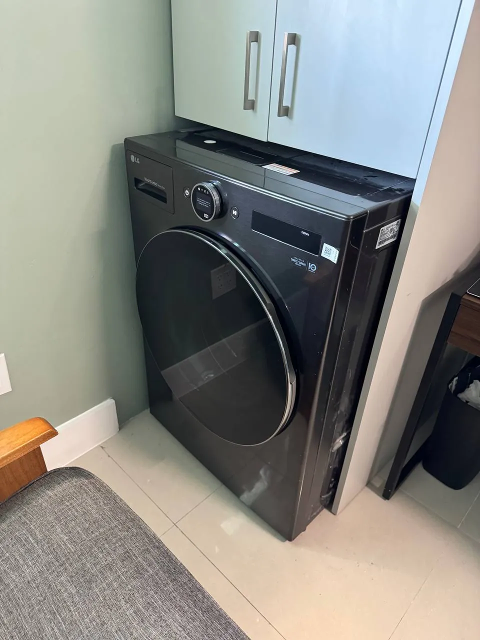 LG washer-dryer combo in black, pulled away from the wall in a home laundry area