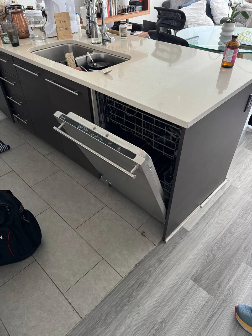 Built-in GE Monogram dishwasher with the door open and both racks visible in a kitchen island