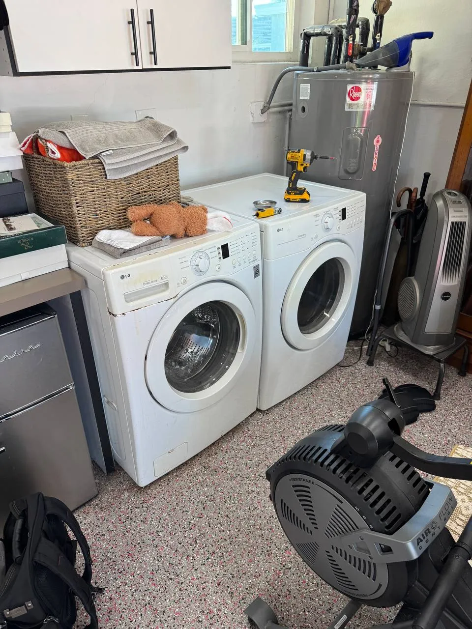 White LG washer and dryer pair with repair tools resting on the dryer