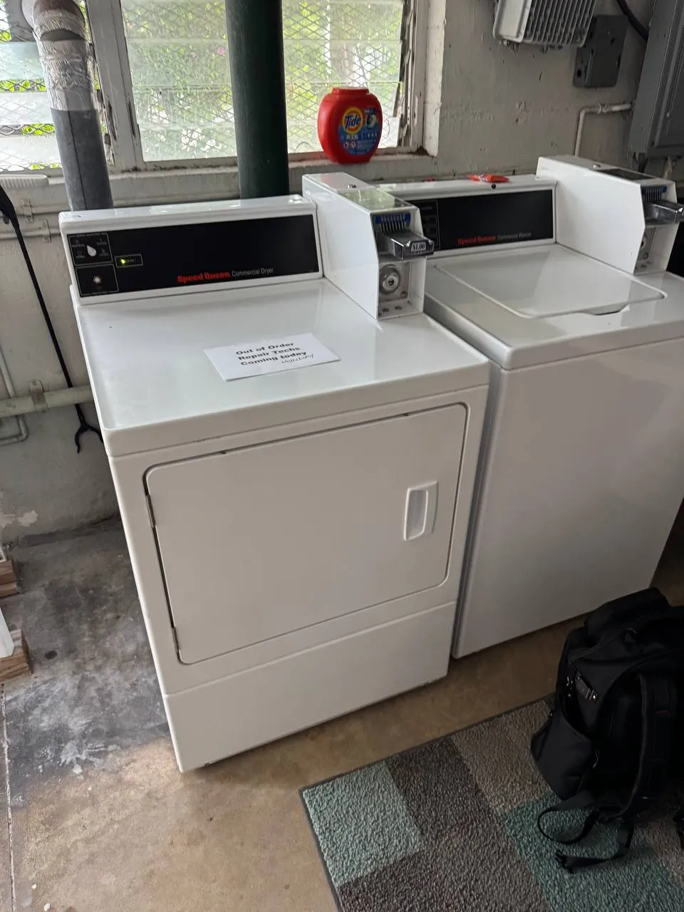 Speed Queen commercial dryer and coin washer in a building laundry room with an out-of-order sign on the dryer