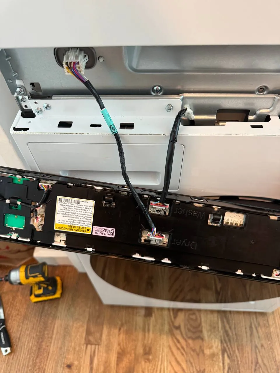 LG laundry center control panel lowered with its wiring visible