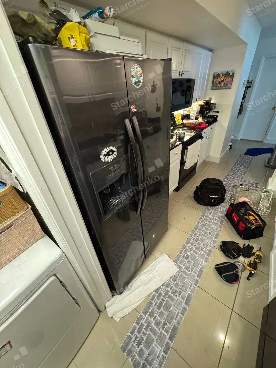 Black Frigidaire side-by-side refrigerator in a white kitchen