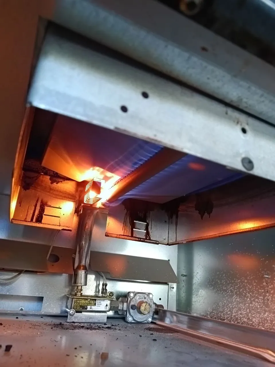 Thermador gas oven with the bottom panel off and the bake burner lit after the repair