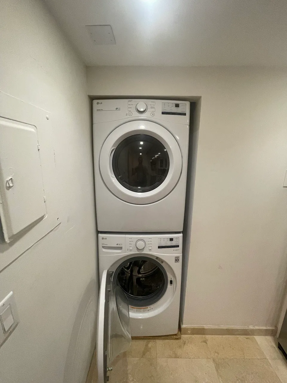 Stacked LG washer and dryer in a tall closet with the washer door open