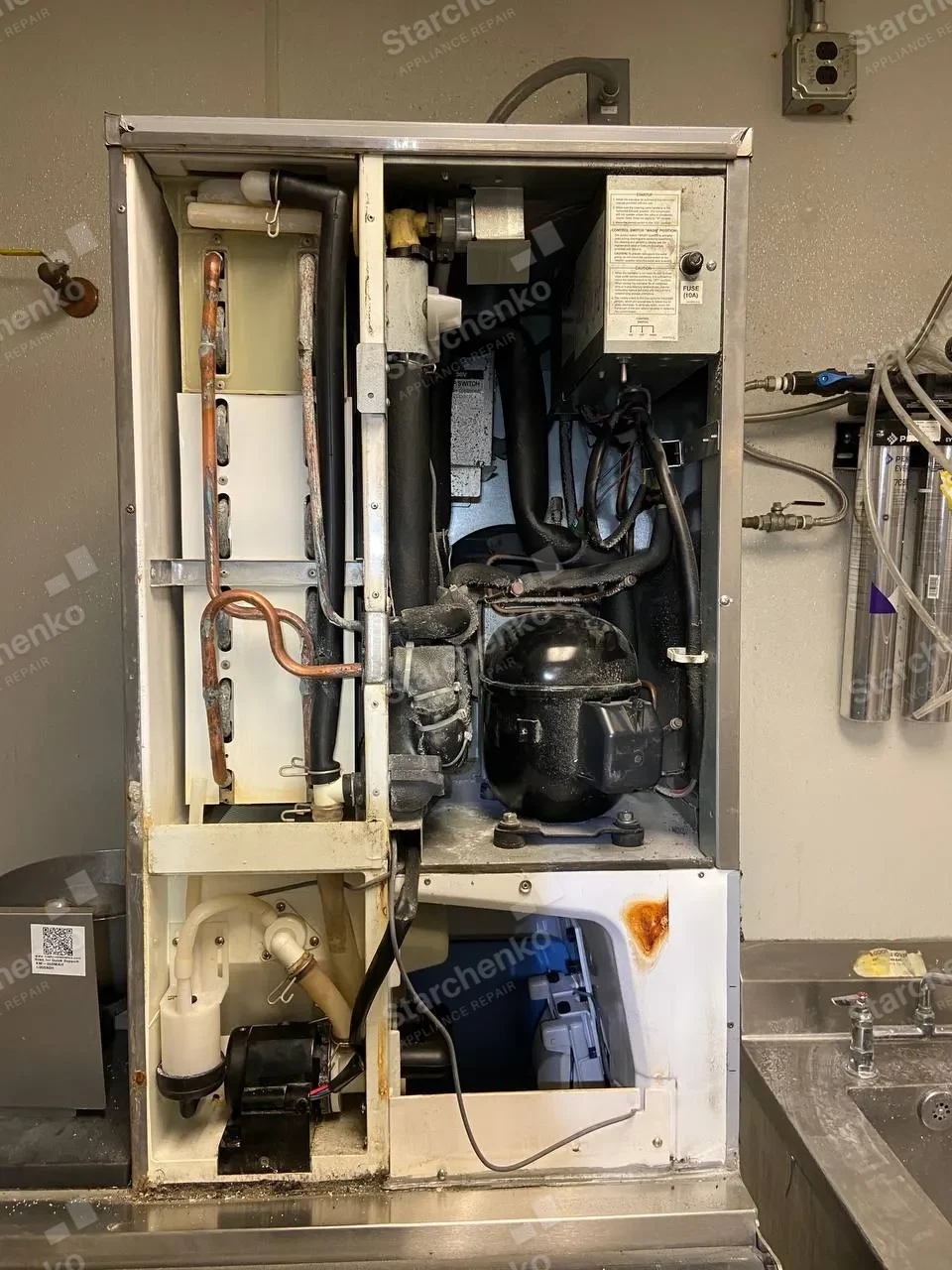 Commercial ice machine with its front panels removed and internal components exposed