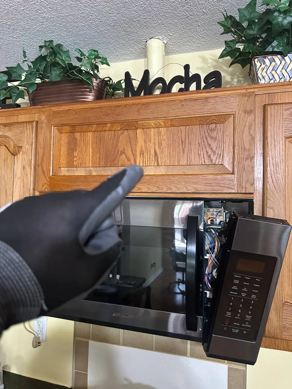 Samsung microwave with its control panel open during a door switch replacement