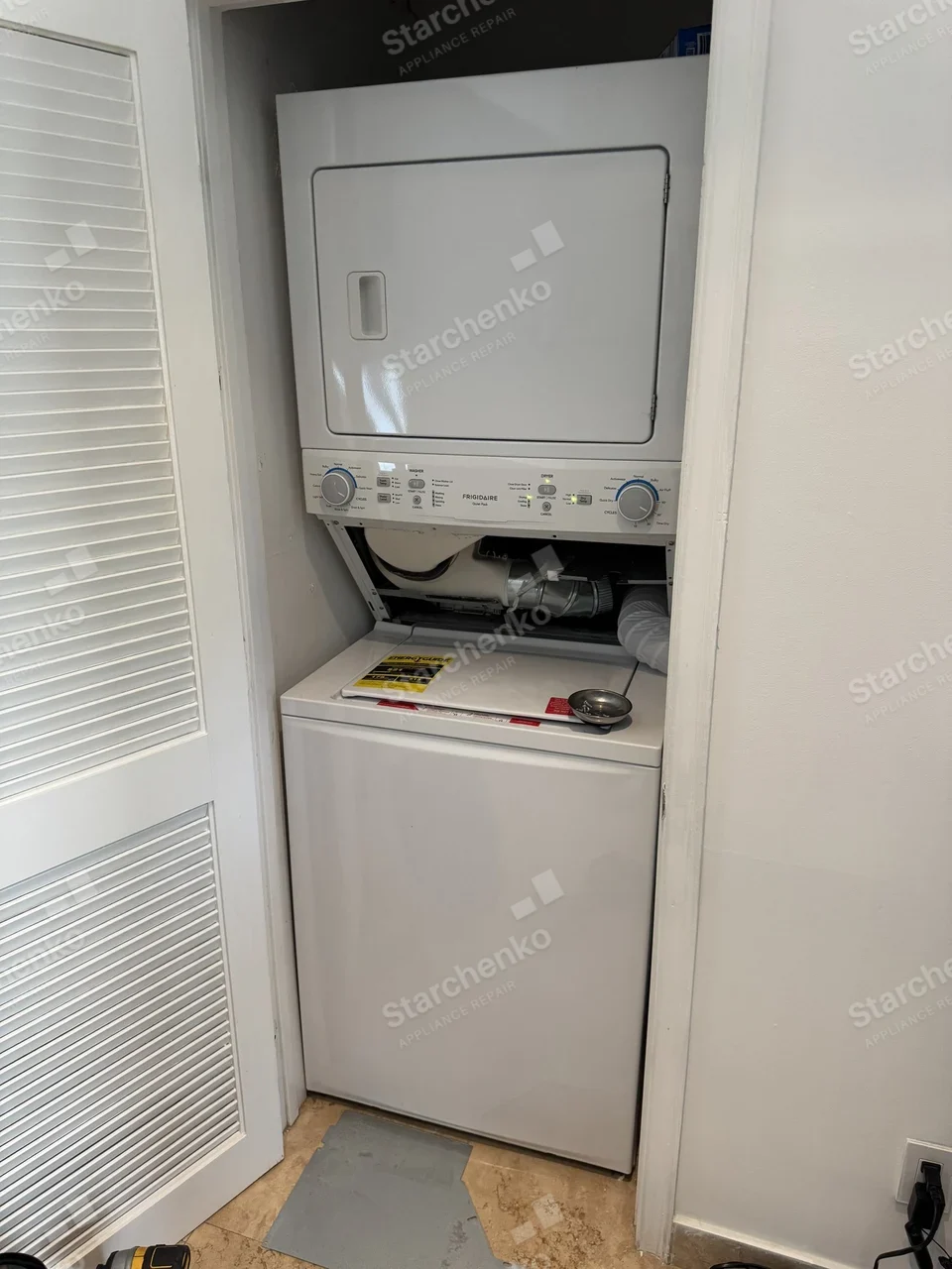 Frigidaire stacked washer and dryer in a closet with the dryer access panel removed and the blower duct exposed