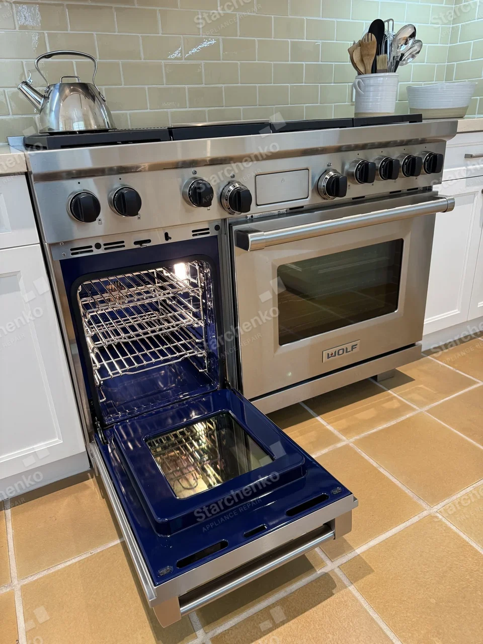 Wolf dual-fuel range with the smaller oven door open and the racks lit
