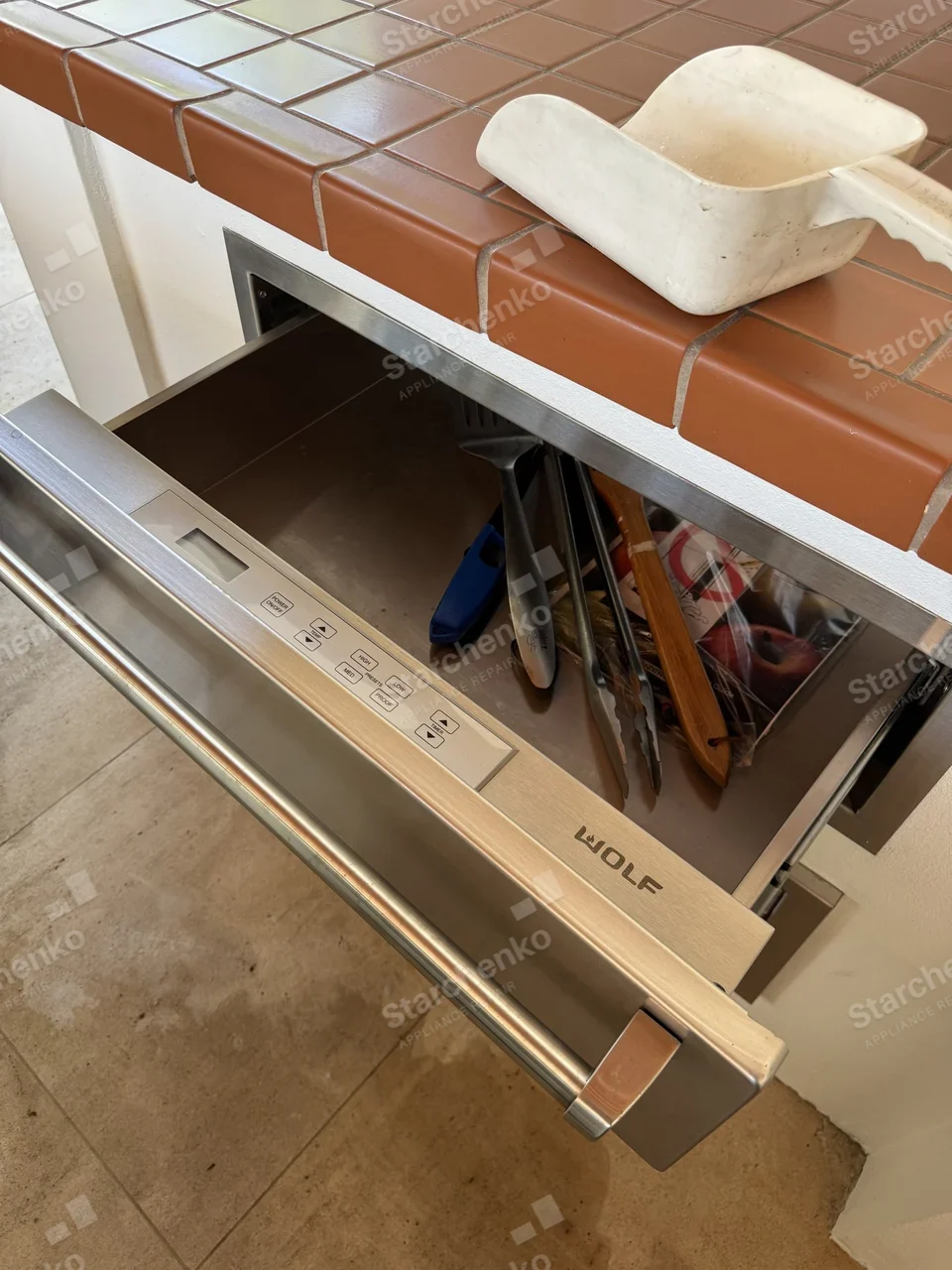 Wolf warming drawer pulled open under a tiled counter