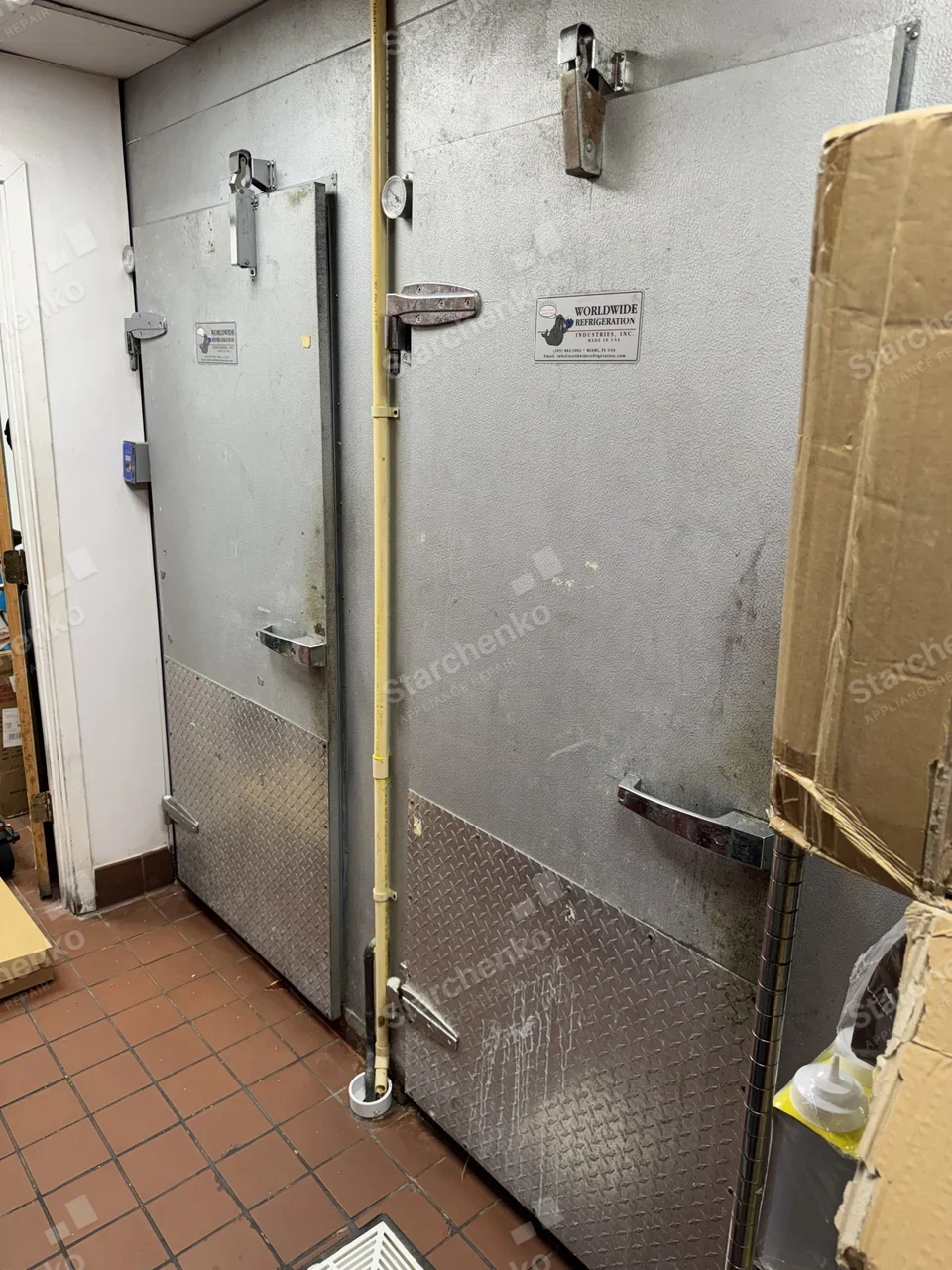 Two walk-in cooler and freezer doors in a restaurant back hallway