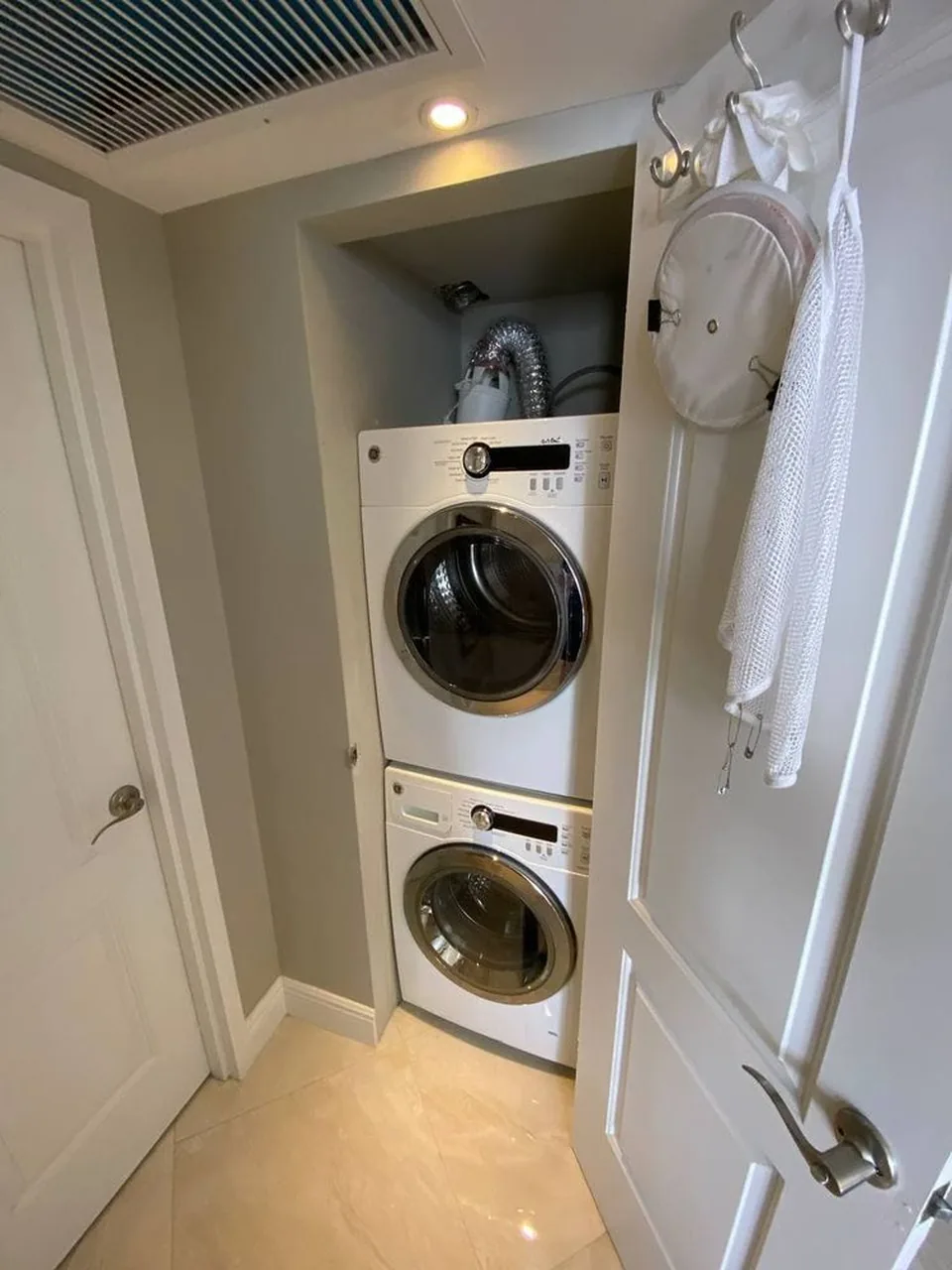 White stacked washer and dryer in a condo closet with the closet door open