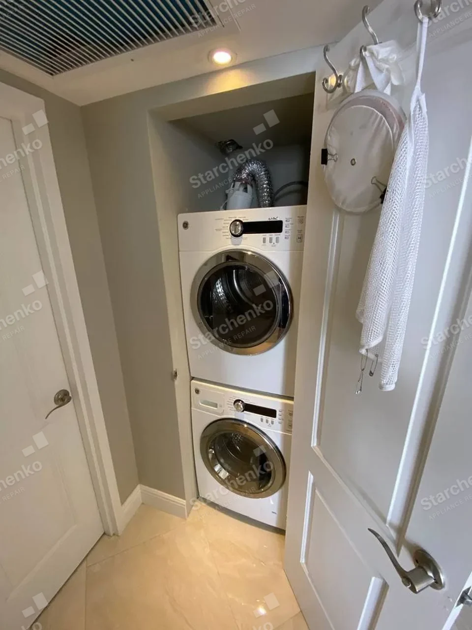 GE white stacked washer and dryer in a condo closet with the closet door open