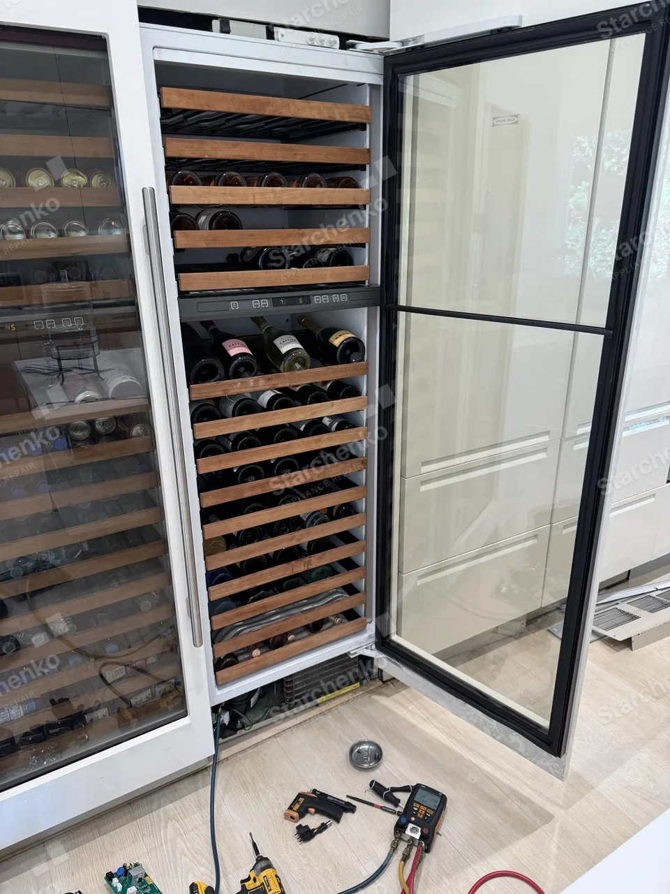 Sub-Zero built-in wine column with the door open, refrigerant gauges connected and a control board on the floor