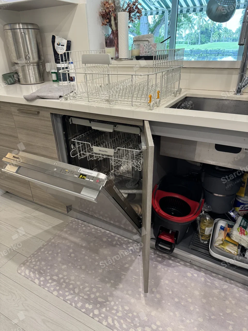 Built-in Miele dishwasher with the door open under a kitchen sink