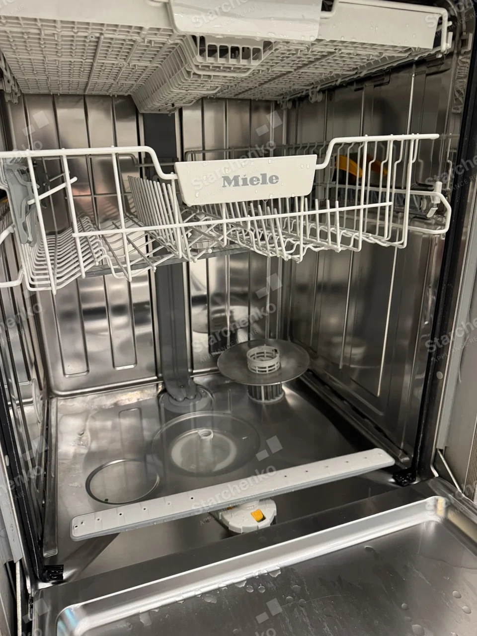 Inside a Miele dishwasher with the lower spray arm removed and the filter exposed