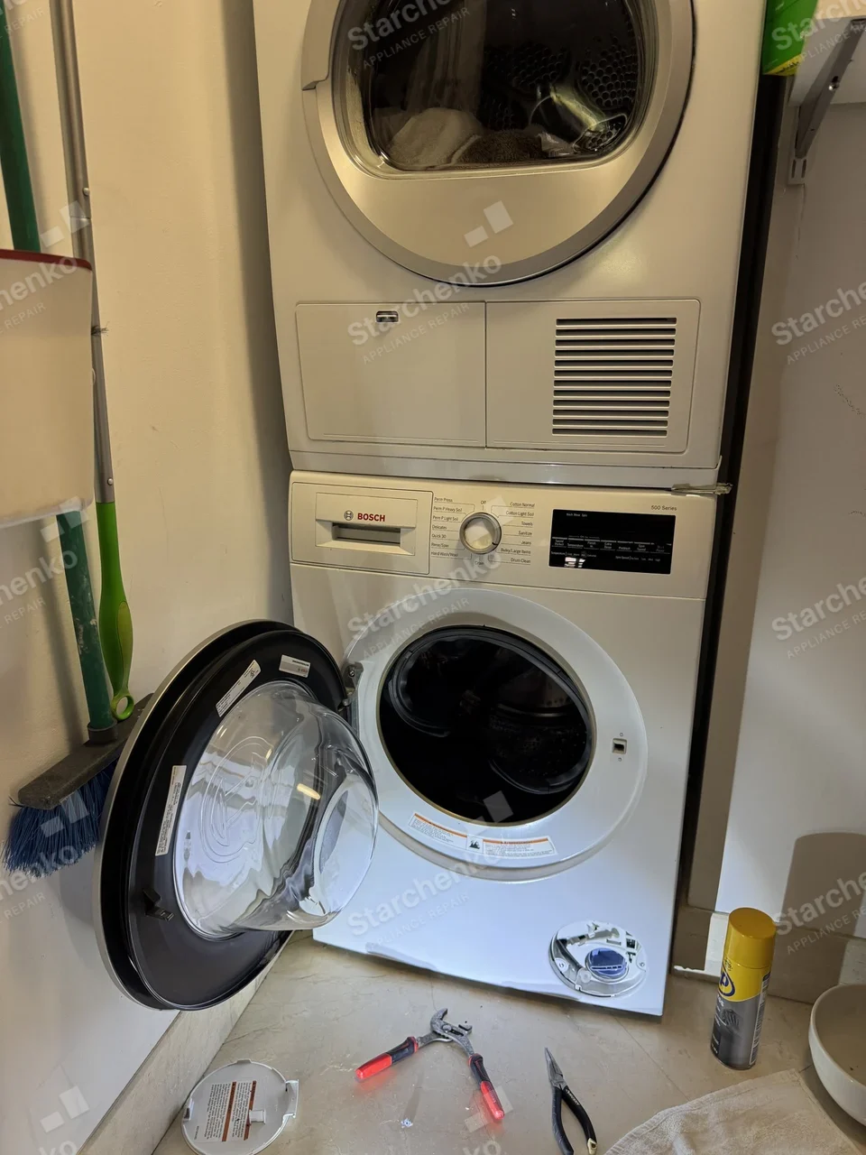 Bosch 500 Series compact washer under a stacked dryer with the drain pump filter cover removed