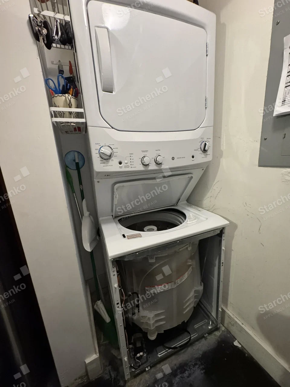 GE stacked washer and dryer with the washer front panel removed and the tub exposed