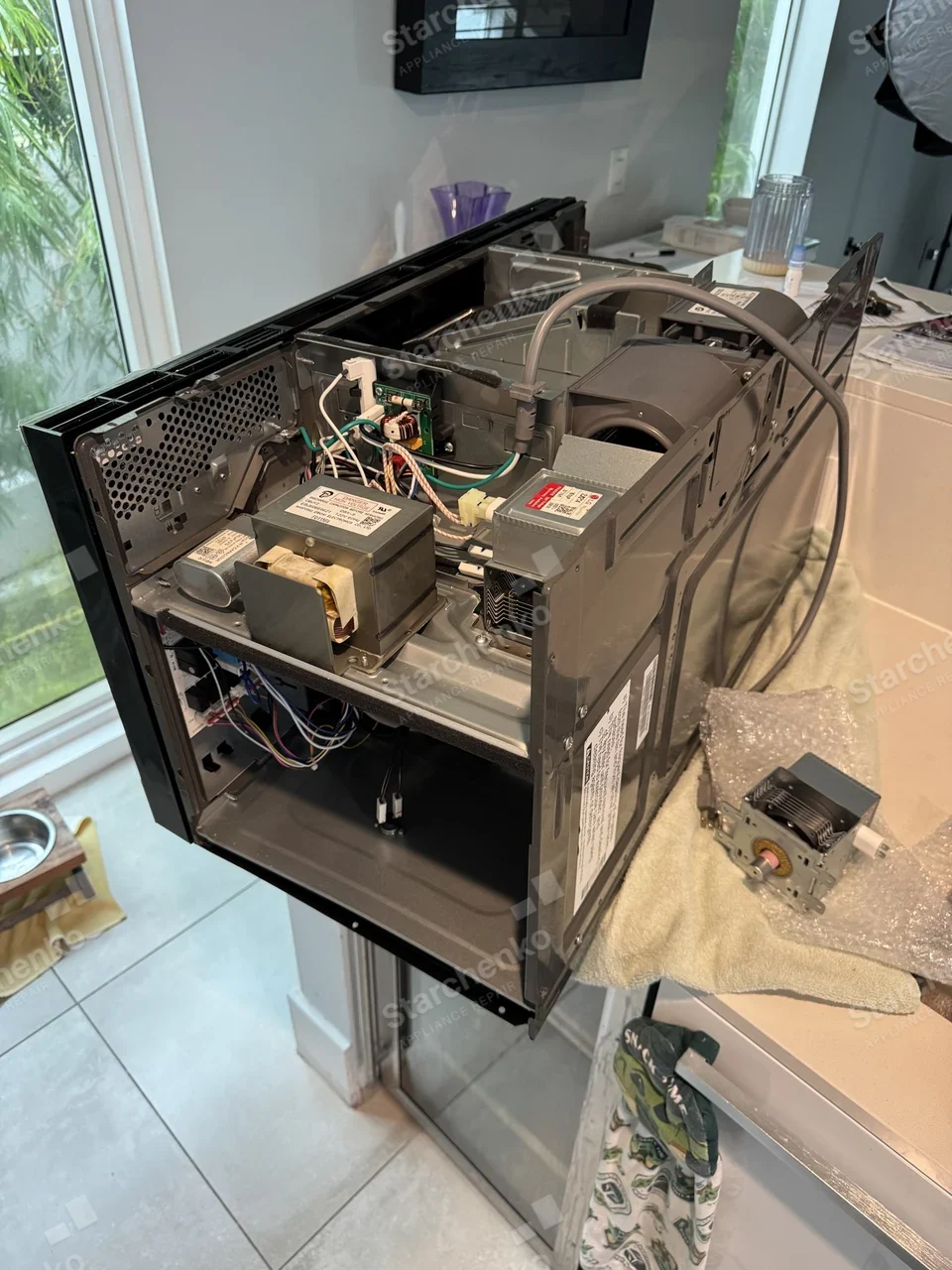 LG over-the-range microwave with the outer case removed and a new magnetron beside it