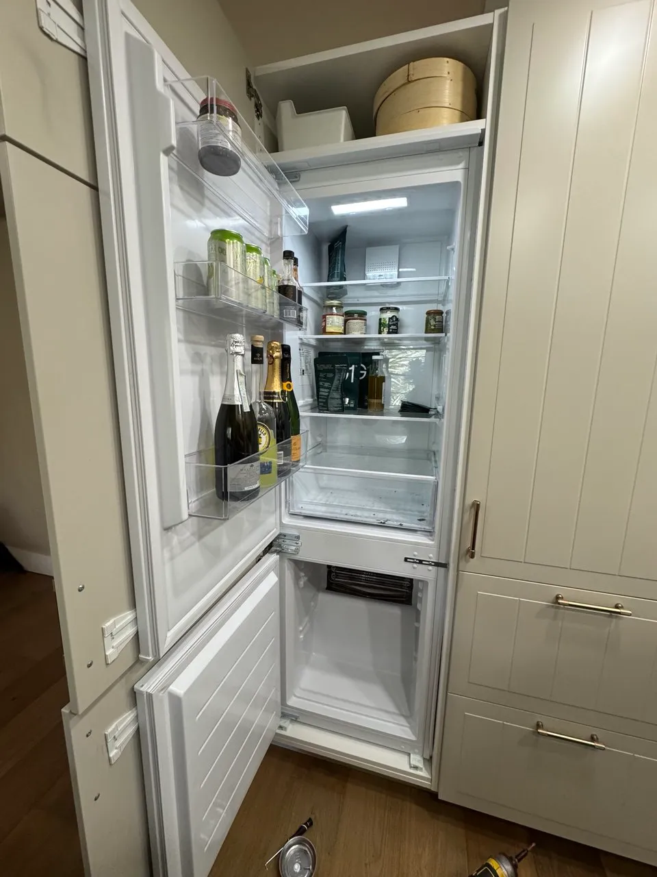 Built-in bottom-freezer refrigerator with its doors open in a white kitchen