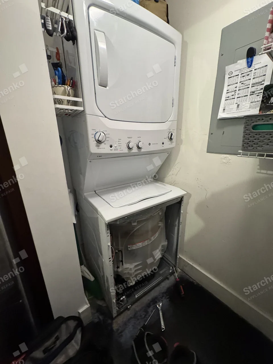 GE stacked washer and dryer in a laundry closet with the washer front panel removed and tools on the floor