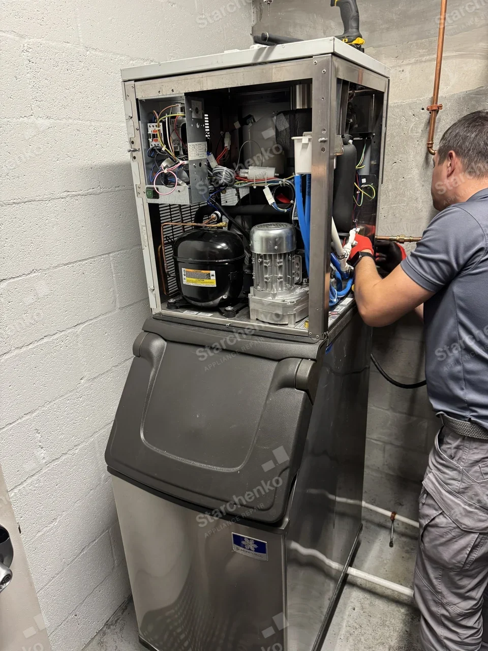 Manitowoc nugget ice machine on its bin with the top panels removed and the compressor and gearmotor exposed