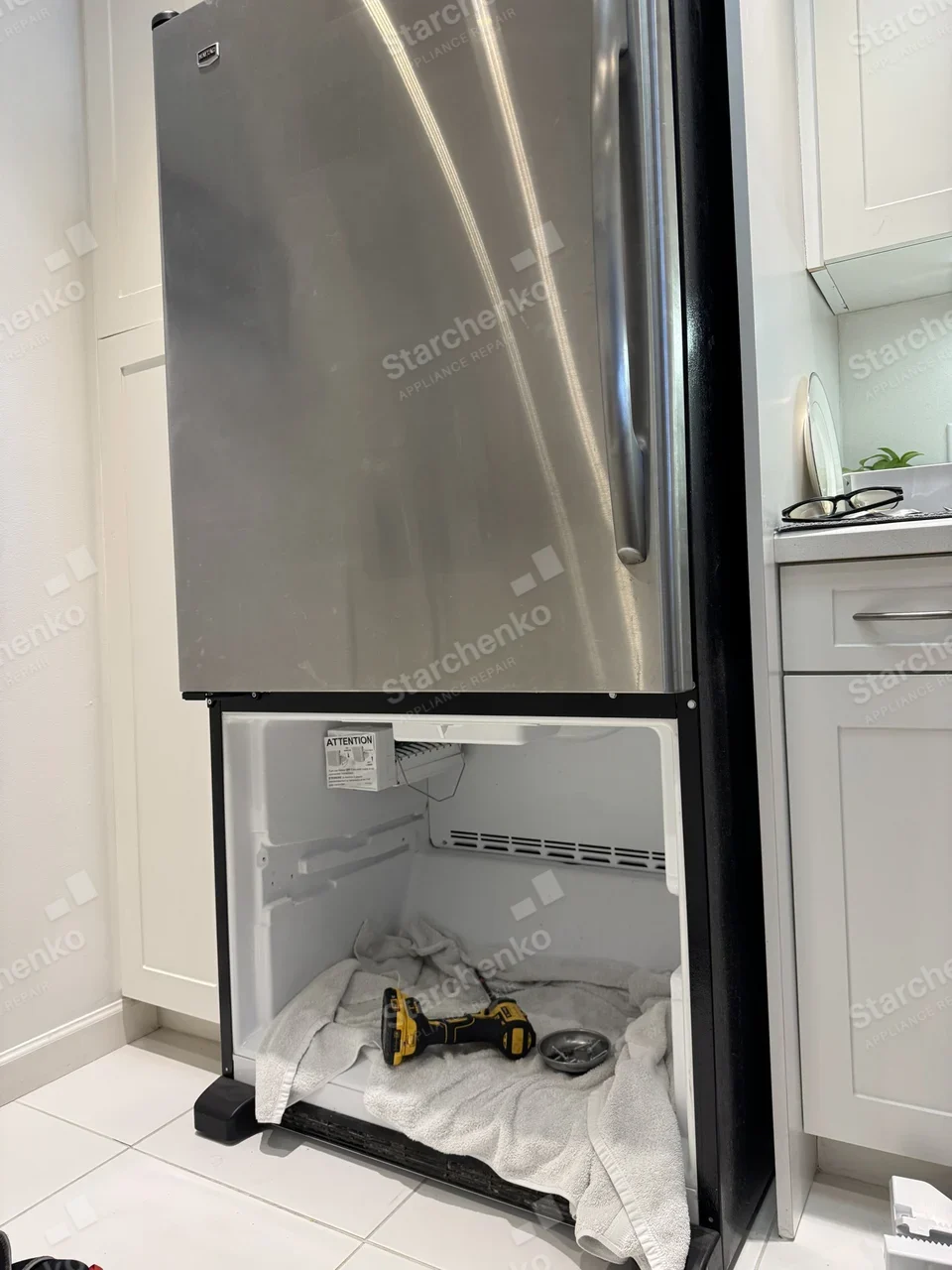 Maytag bottom-freezer refrigerator with the freezer drawer removed and a drill resting inside