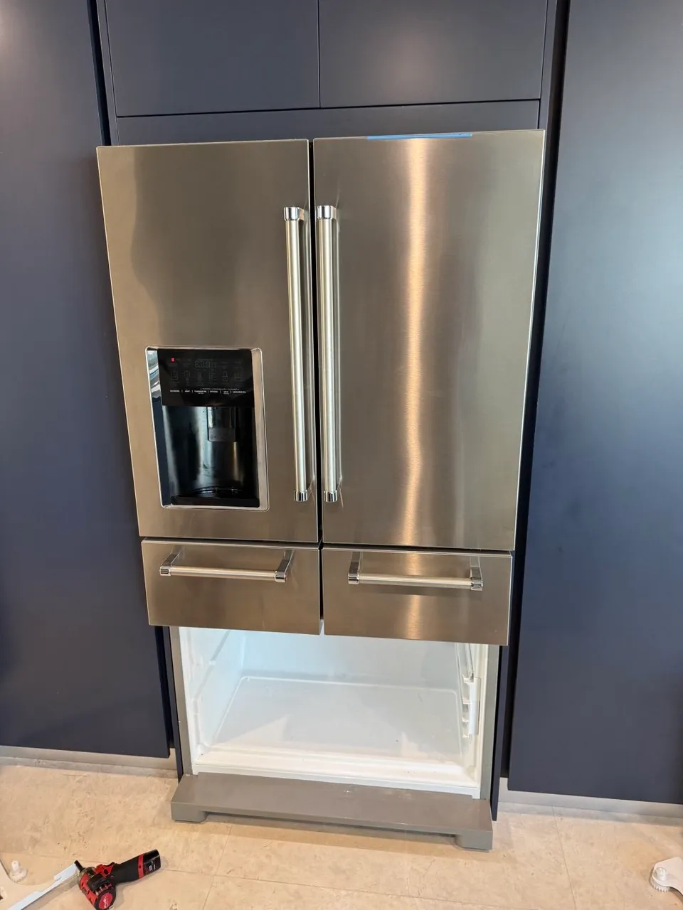 Stainless french-door refrigerator with the freezer drawer pulled out for repair