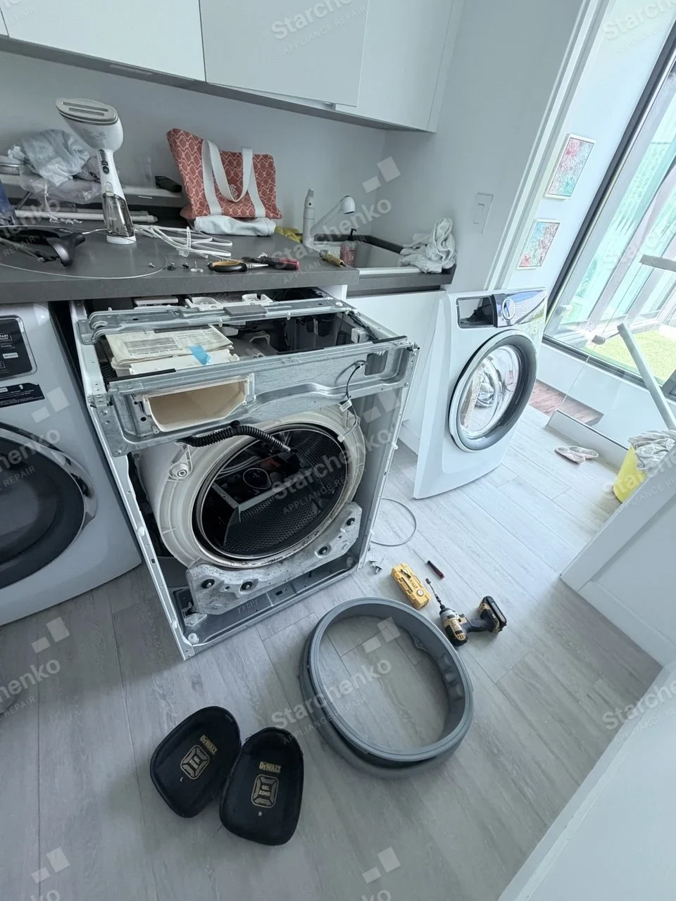 Electrolux front-load washer with the front panel removed and the door boot seal on the floor