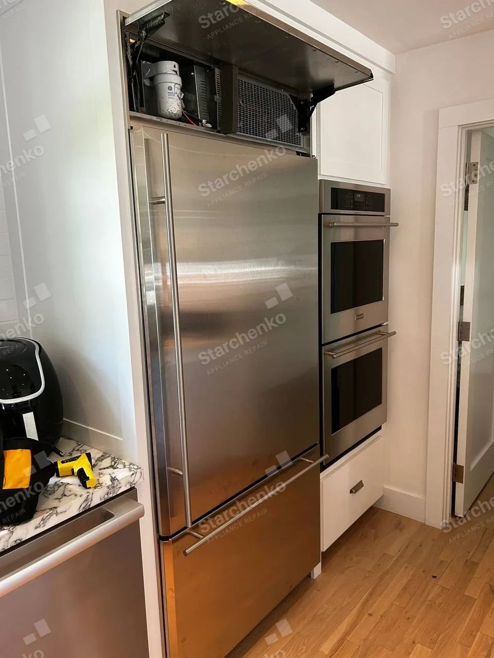Miele repair: Full-height stainless built-in refrigerator with lower freezer drawer and raised upper compressor-service cover.
