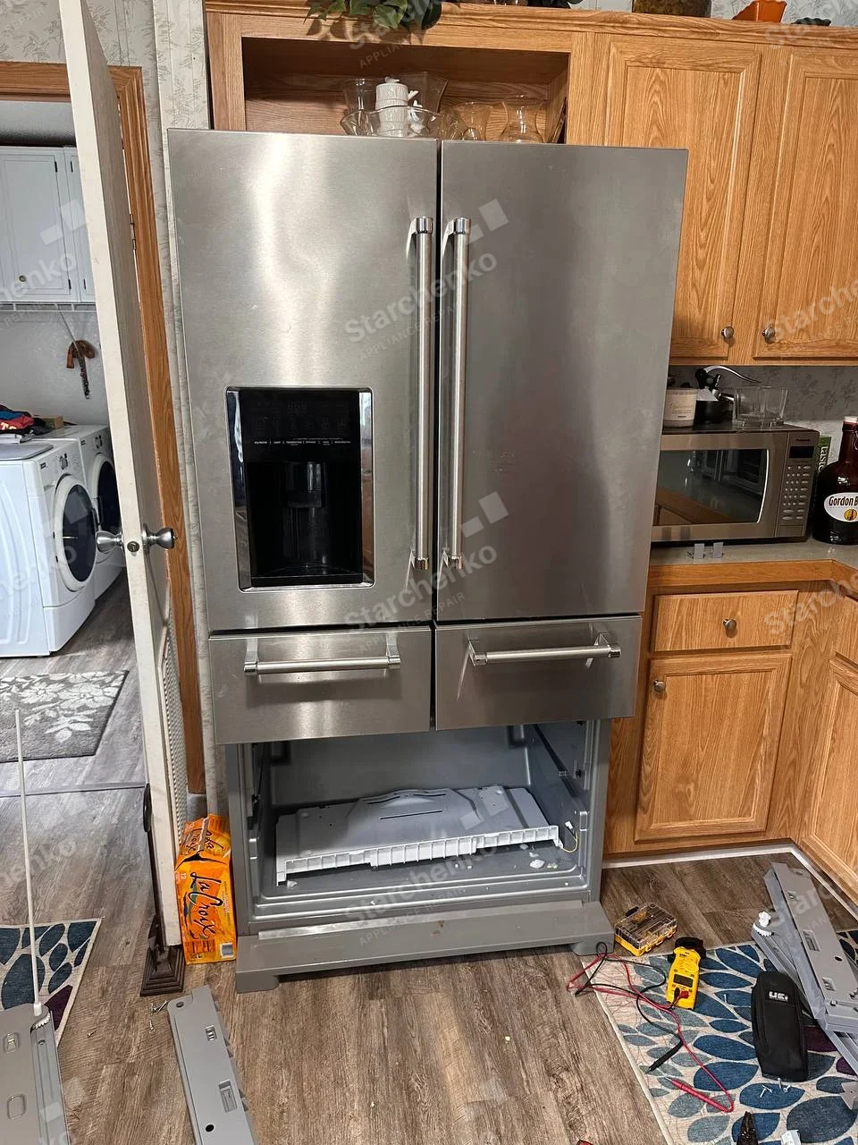 Samsung repair: French-door refrigerator with twin lower drawers and bottom machine compartment opened for repair.