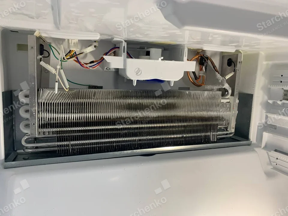 Samsung repair: Refrigerator freezer compartment with interior panel removed, exposing horizontal evaporator coil and wiring.