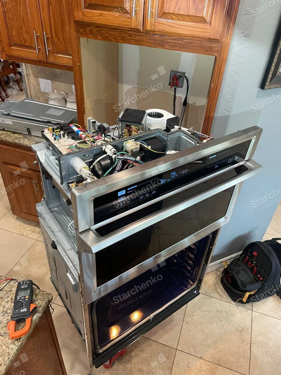 SAMSUNG lettering on oven door lower trim, unit pulled out, top cover removed exposing electronics and cooling blower.