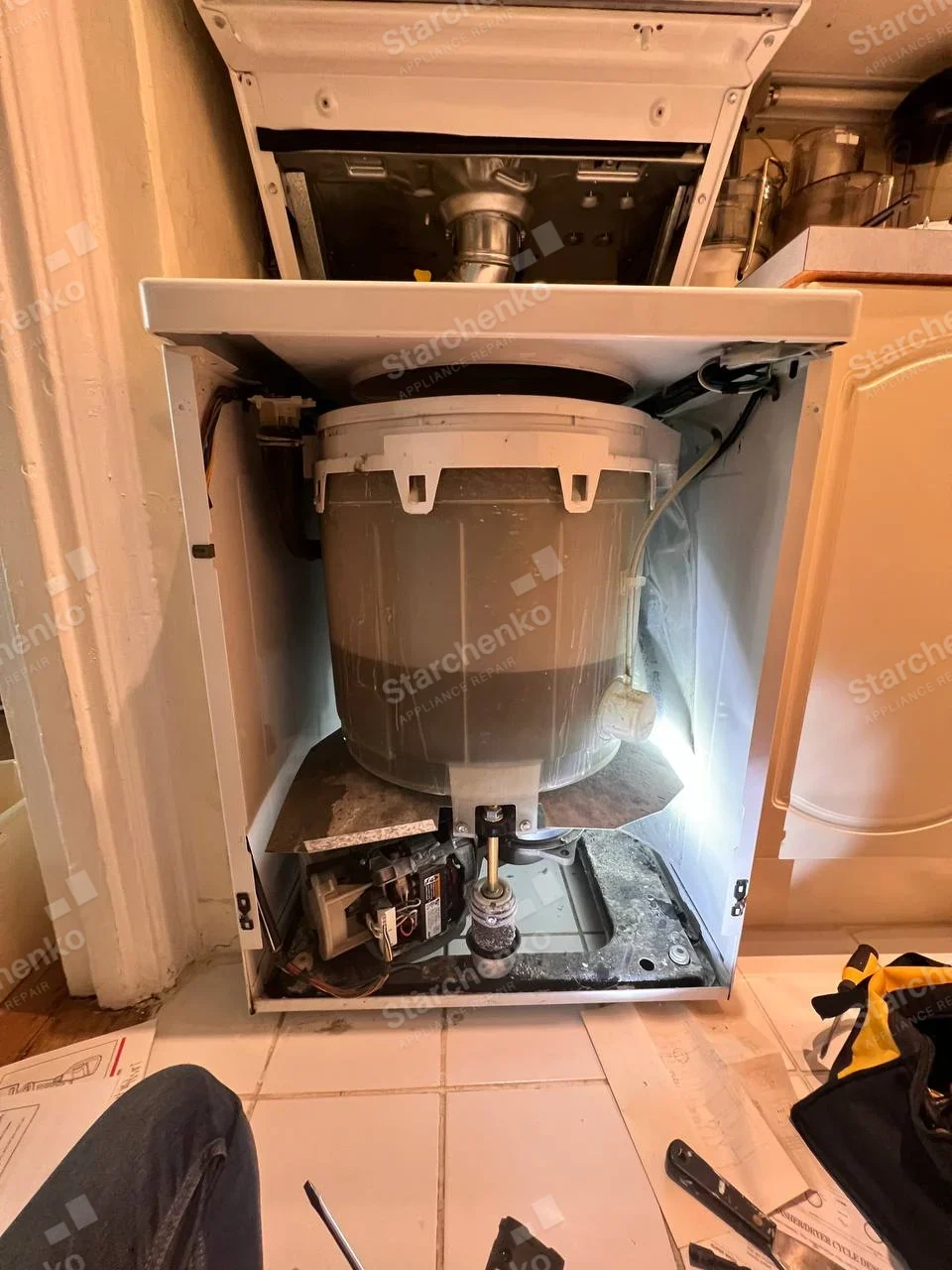 Amana repair: Front panel of lower unit removed, showing large cylindrical wash tub, bottom drive shaft and drain pump, dryer vent section immediately above.