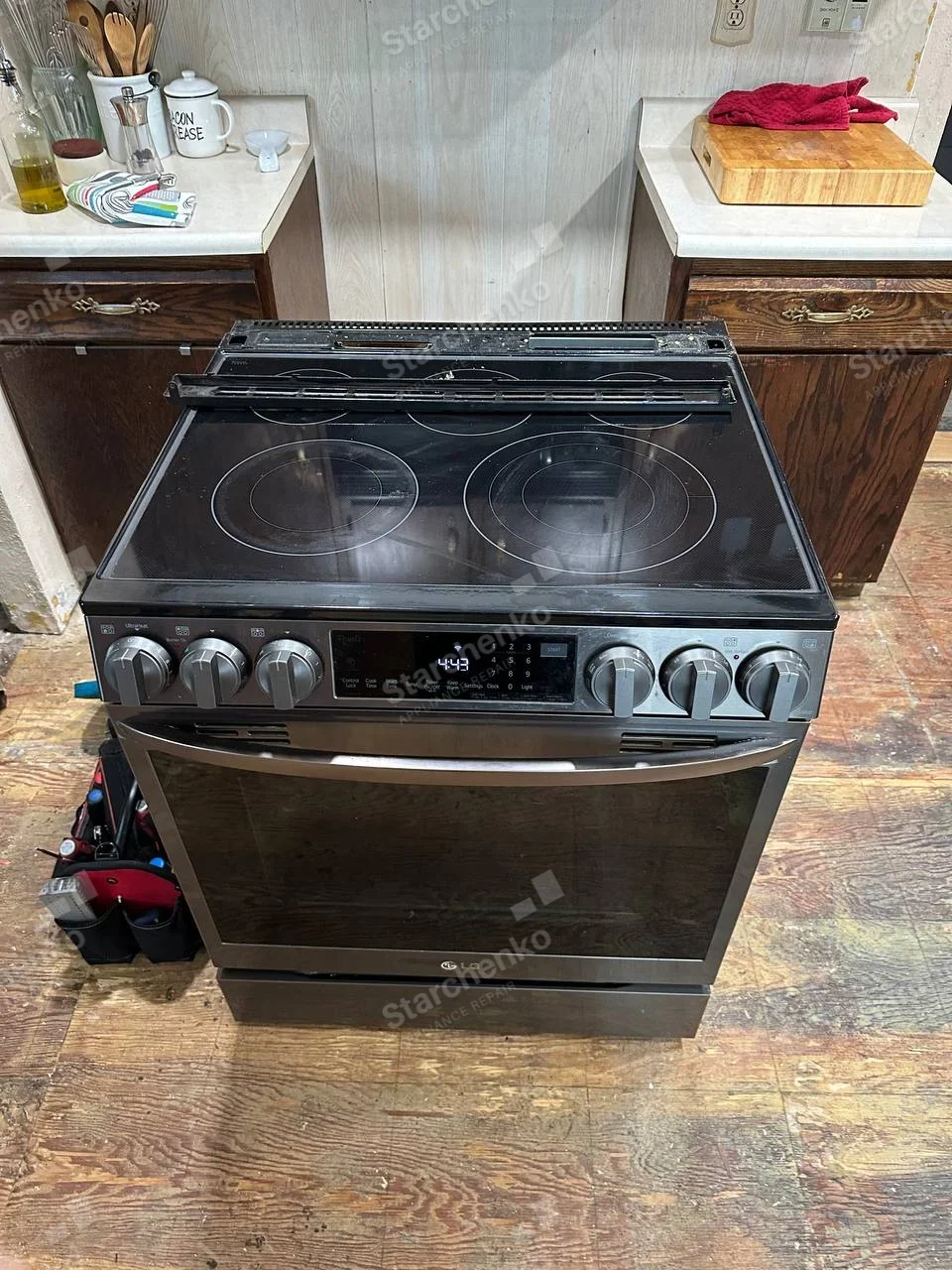 LG electric smooth-top range pulled away from cabinetry with rear cooktop trim removed.