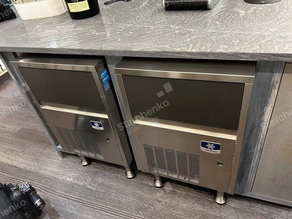 Manitowoc repair: Two adjacent undercounter commercial ice machines with front vents under a counter.
