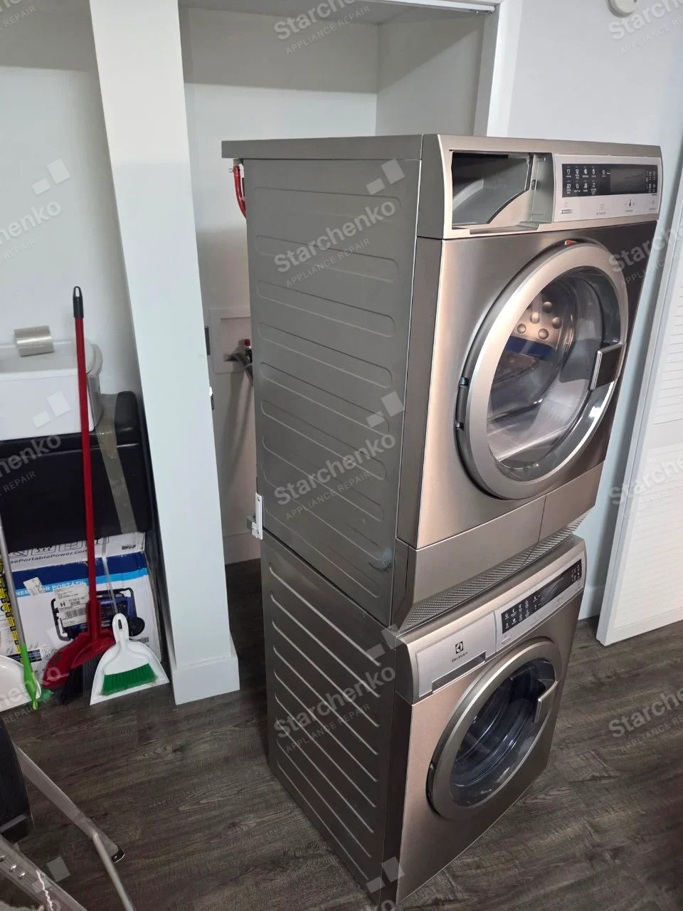 Whirlpool repair: Upper front-load laundry machine pulled from stacked installation, lower washer bears Electrolux badge, but upper dryer has no clear mark.