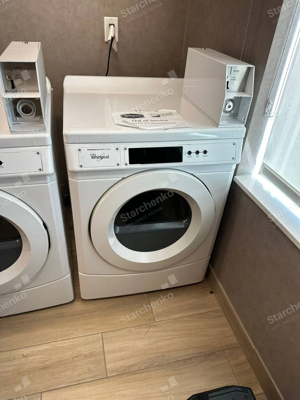 Whirlpool commercial front-load dryer with coin box and out-of-service notice on top.