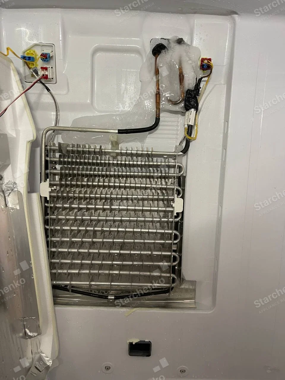 LG repair: Exposed refrigerator freezer evaporator coil and copper tubing with ice near the top.