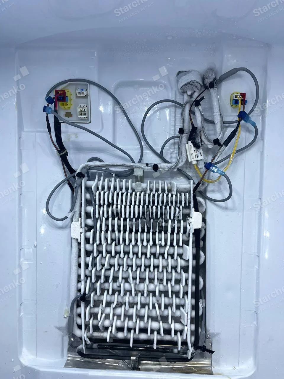 LG repair: Exposed freezer evaporator coil with frost on fins and surrounding wiring.