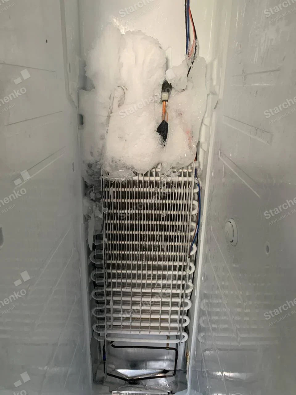 LG repair: Exposed refrigerator evaporator coil with heavy ice buildup near top and wiring alongside.