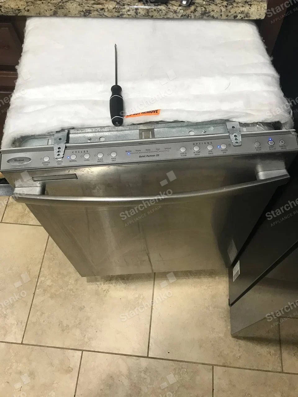 Whirlpool Quiet Partner III dishwasher pulled out with top control strip and insulation blanket visible.