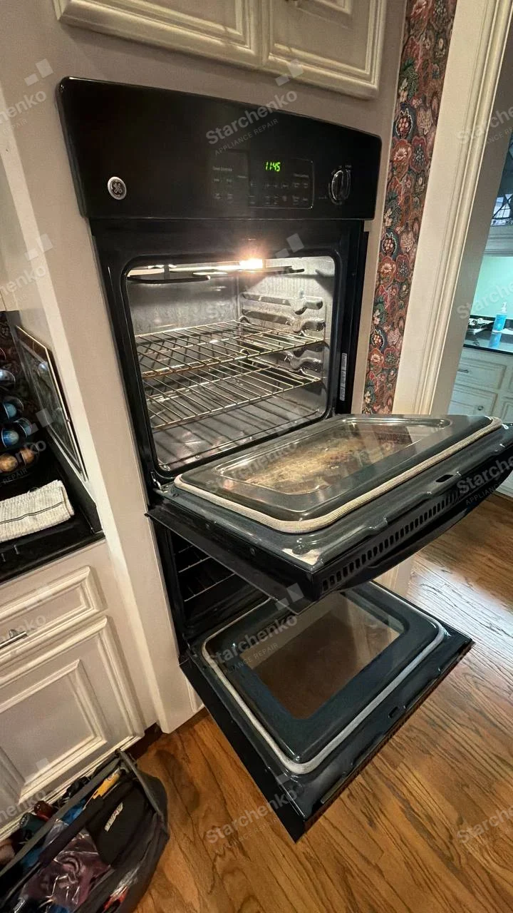GE monogram on the upper-left fascia of the open double wall oven.
