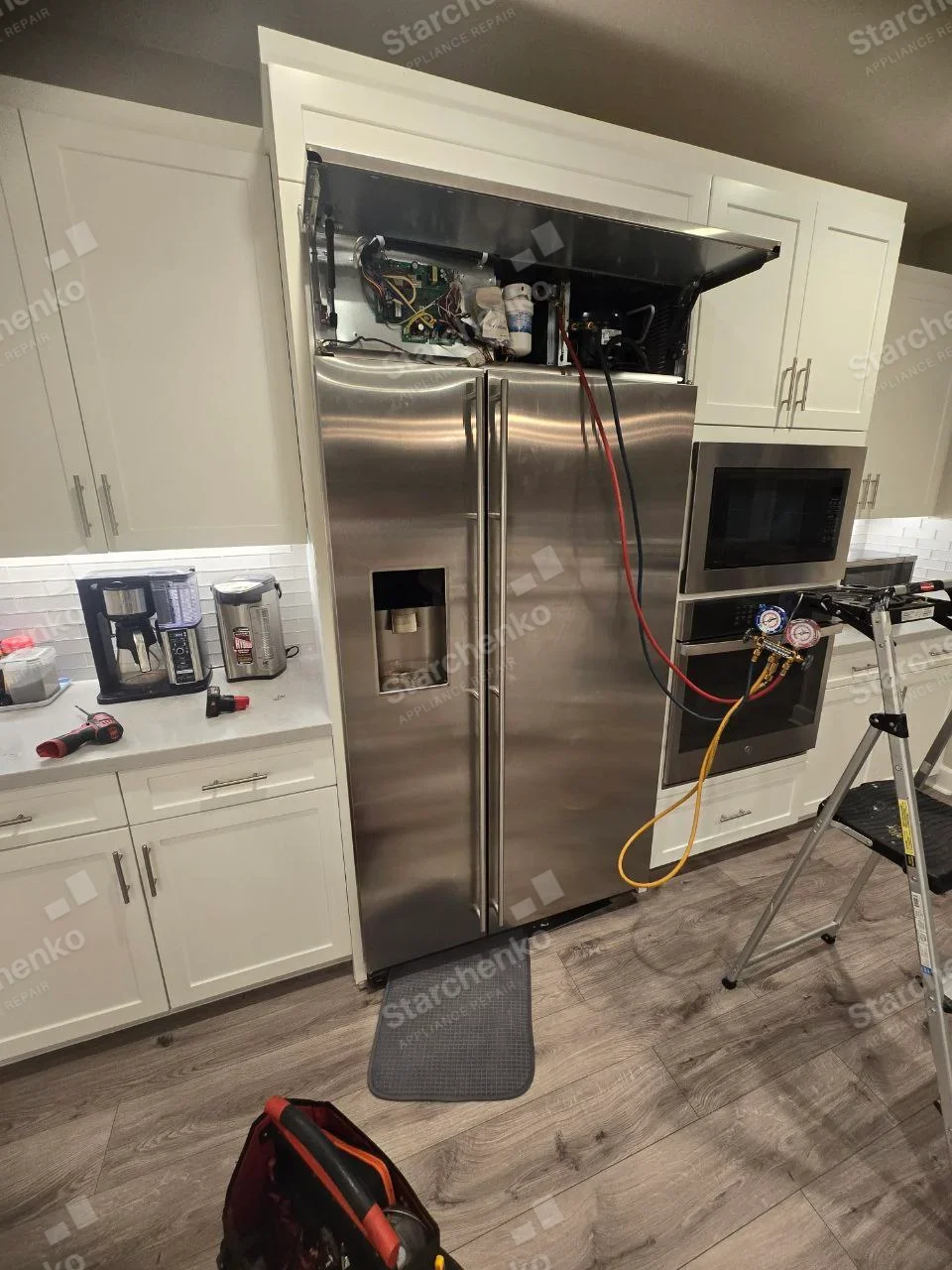 Miele repair: Tall built-in side-by-side refrigerator, top service cover raised with refrigeration gauges connected.